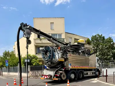 Camion hydrocureur avec bras de pompage déployé sur un chantier